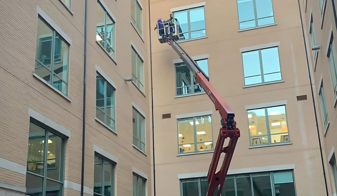 Commercial window cleaners using a hydraulic platform to clean a high-rise building.