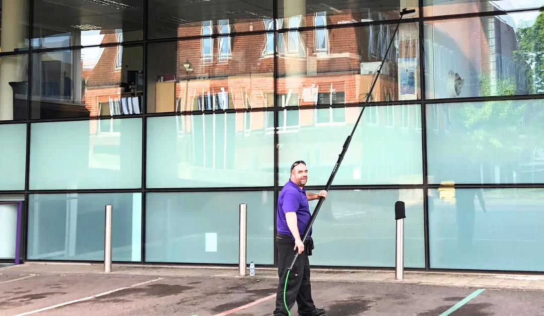 Windoew cleaner using extended pole to clean office windows.