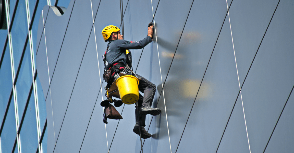 Man cleaning the cladding on building.