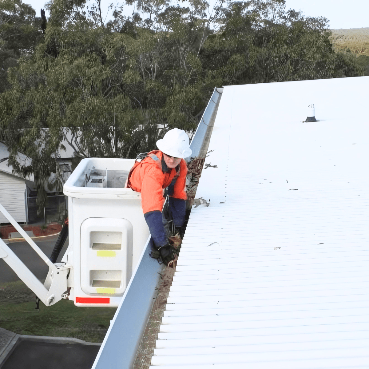 Man cleaning gutter of commercial building.