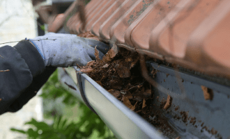 Hand picking leaves out and cleaning gutter.