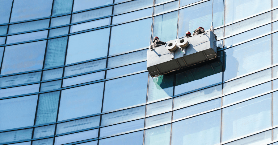 Commercial window cleaners cleaning building facade using a cradle.