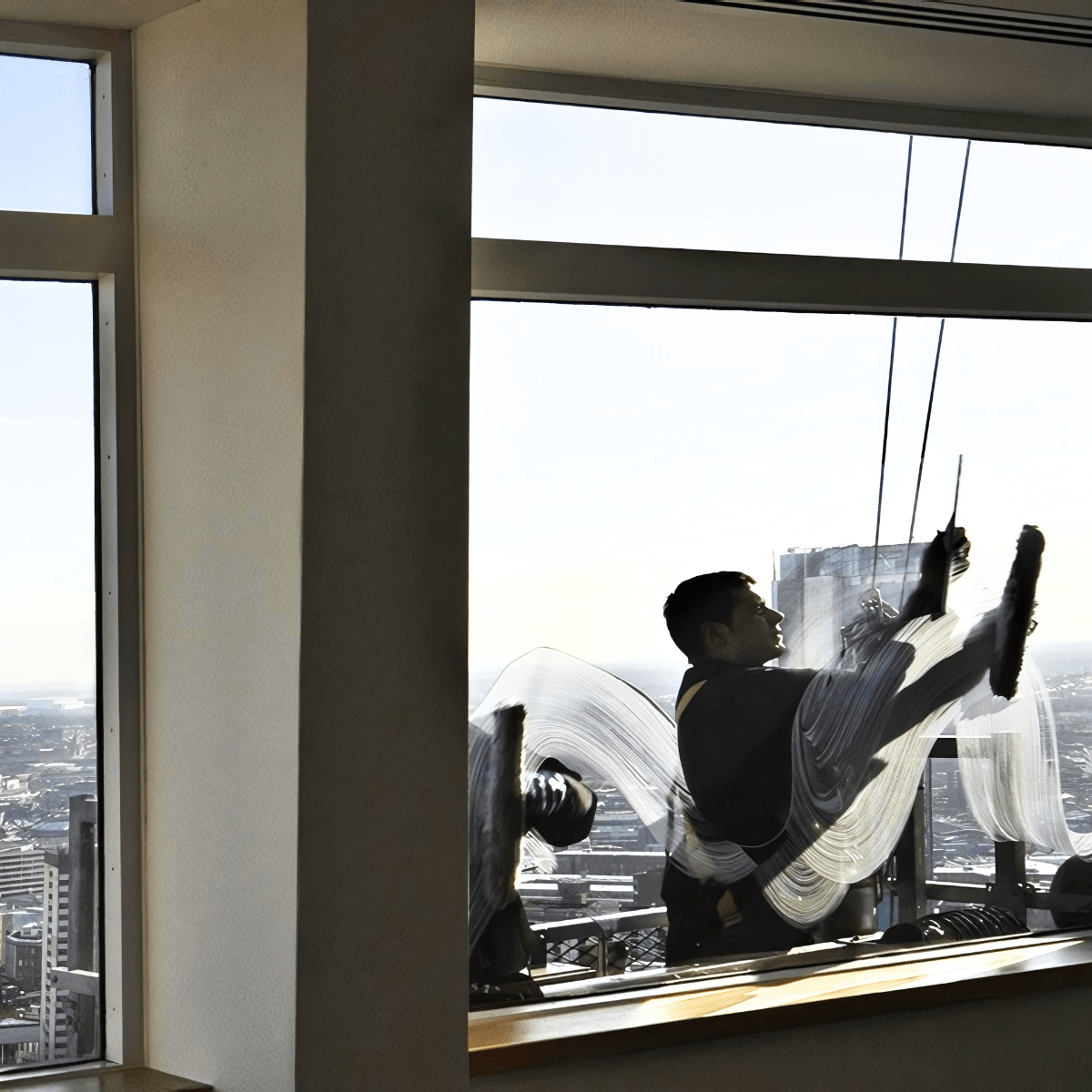 Man cleaning commercial high rise building using rope access.