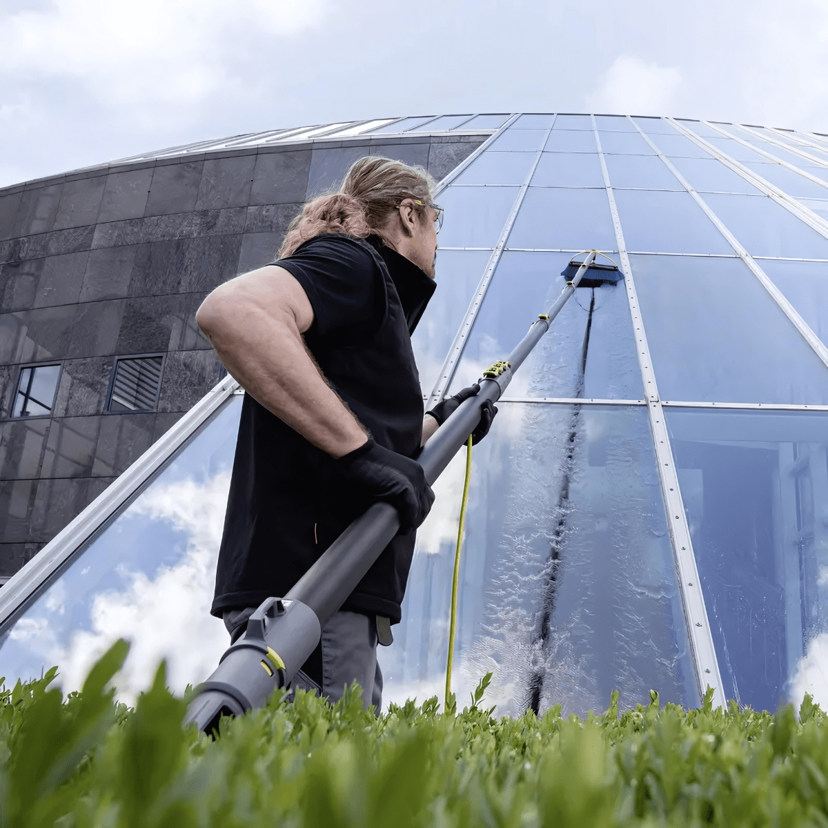 Man using a water-fed pole system to clean office windows