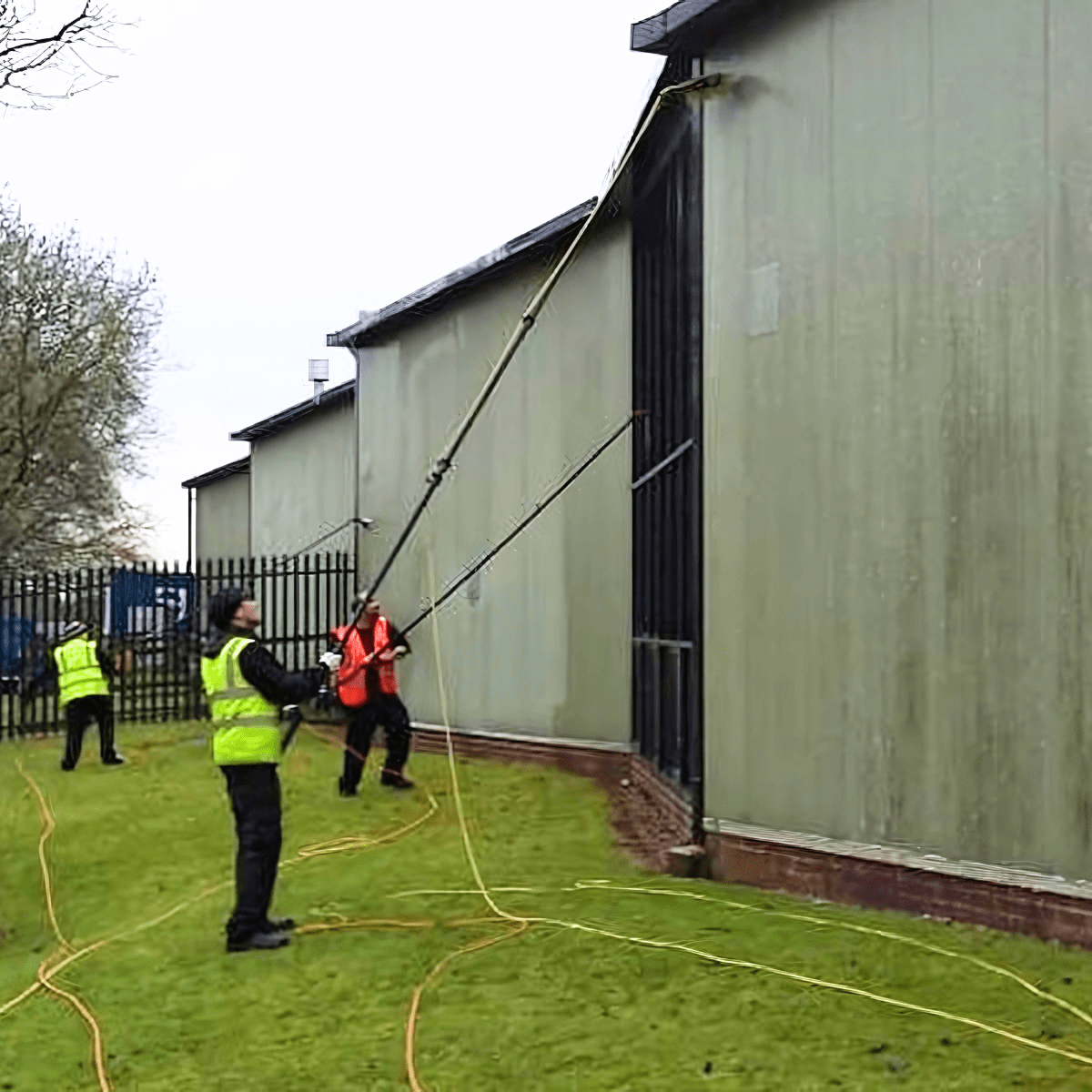 Three men washing the cladding on a building.