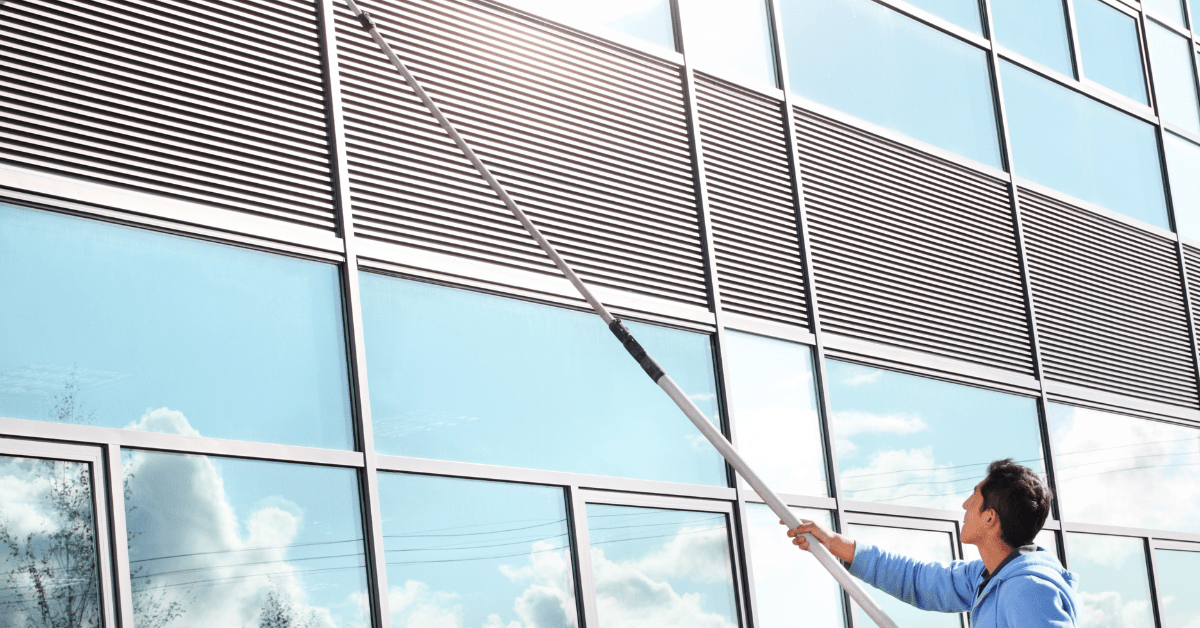 Commercial window cleaning man using water fed pole system to clean windows