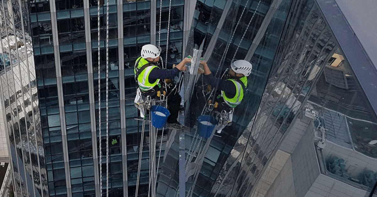 Man cleaning high level window with reflection in the glass.