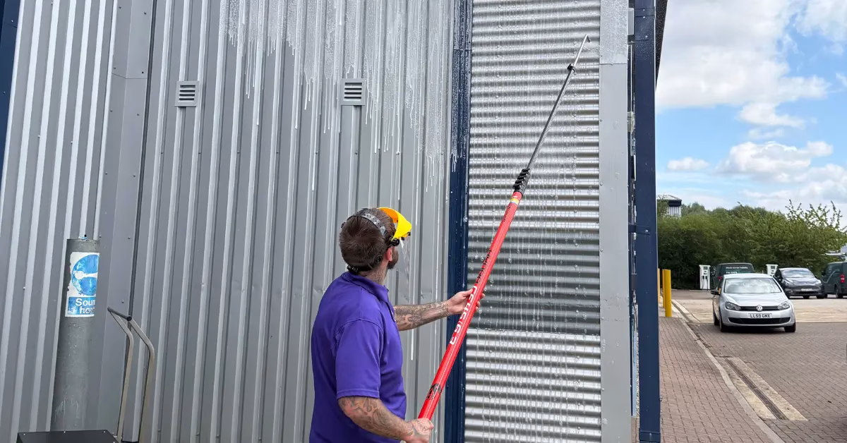 Clifton staff using soft washing system to clean cladding.