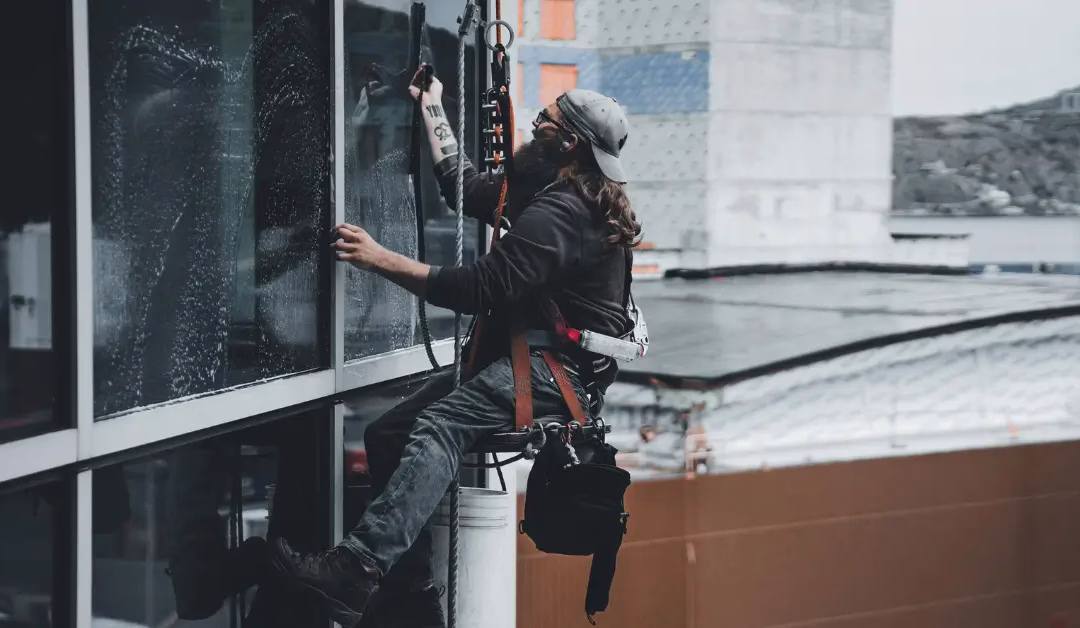 Rope access window cleaner cleaning windows on a high rise building.